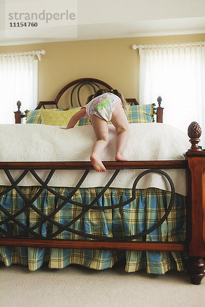 Rückansicht eines kleinen Mädchens beim Klettern im Bett