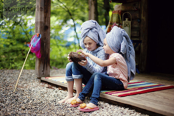 Kaukasische Schwestern mit Haartüchern  die ein Vogelnest untersuchen