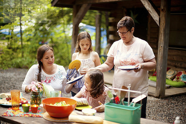 Drei Generationen von kaukasischen Frauen kochen vor der Hütte
