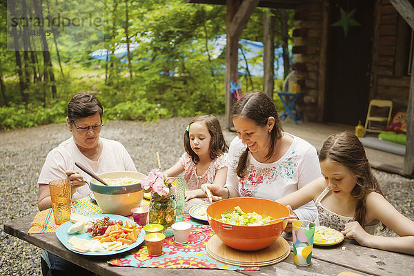 Drei Generationen kaukasischer Frauen essen außerhalb der Hütte
