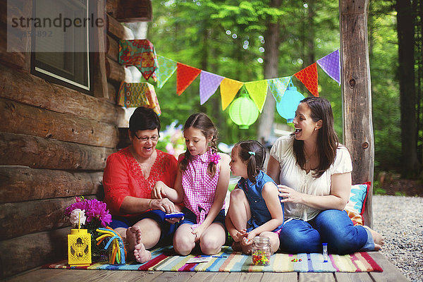 Drei Generationen von kaukasischen Frauen spielen mit Spielzeug auf der Veranda einer Hütte