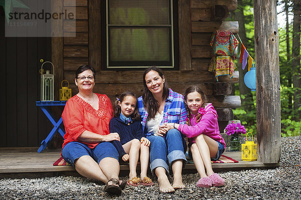Drei Generationen kaukasischer Frauen lächelnd auf der Hüttenveranda