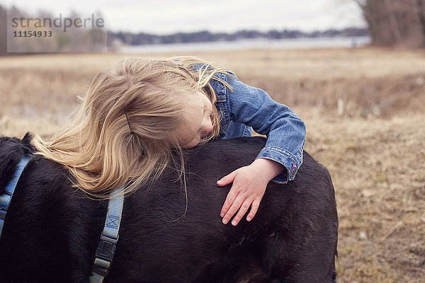 Nahaufnahme eines Mädchens  das einen Hund auf einem ländlichen Feld umarmt