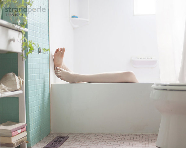 Beine einer kaukasischen Frau beim Entspannen in der Badewanne