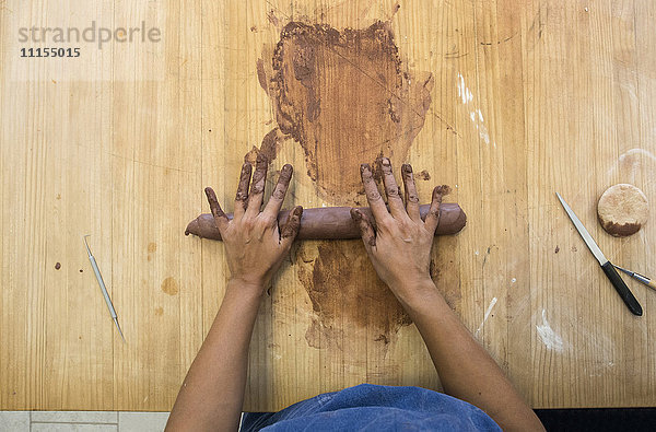 Hände einer Frau bei der Arbeit mit Ton in einer Keramikwerkstatt
