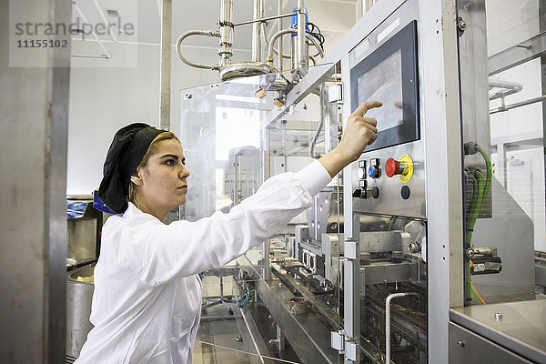 Frau  die eine Maschine bei der Herstellung von Schokolade in einer Fabrik bedient