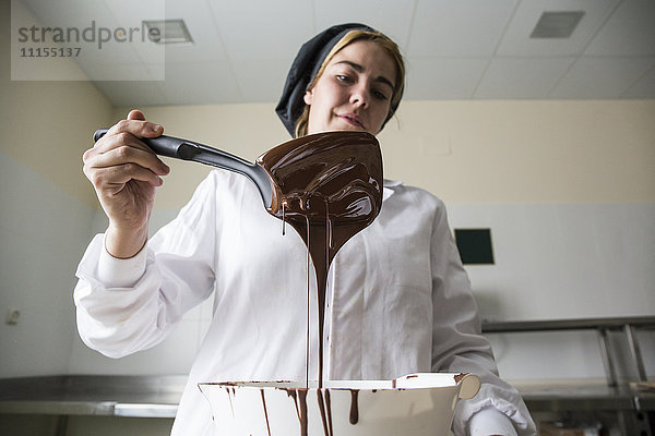 Frau kontrolliert die Dicke der geschmolzenen Schokolade