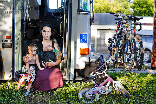 Mutter und Kinder sitzen in der Tür des Busses