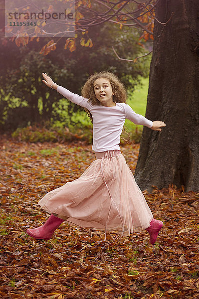 Kaukasisches Mädchen springt vor Freude im Herbstlaub