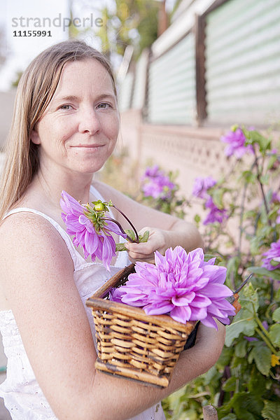 Gemischtrassige Frau pflückt Blumen im Garten