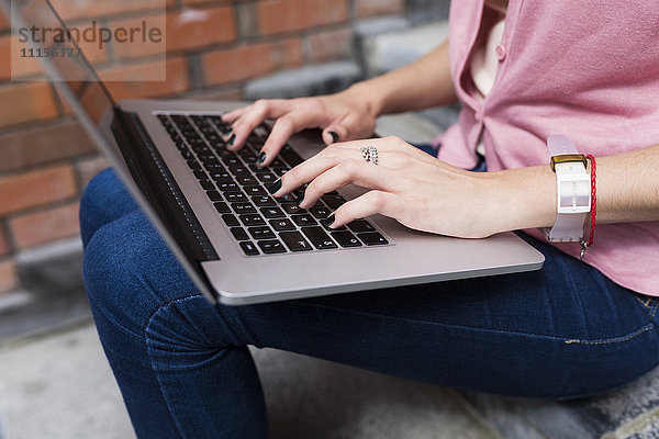 Die Hände der Frau auf der Tastatur des Laptops
