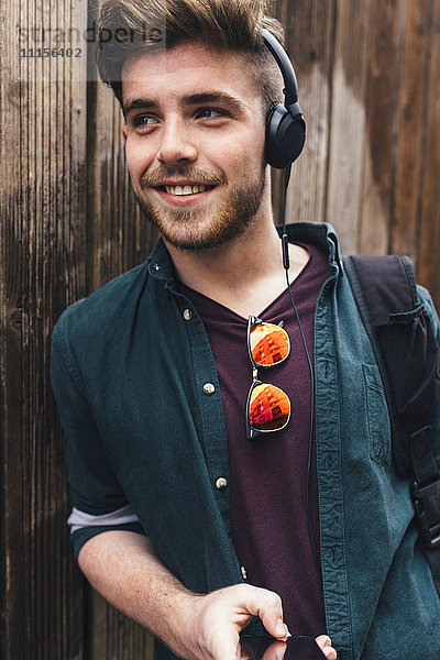 Portrait eines glücklichen jungen Mannes beim Musikhören mit Kopfhörern