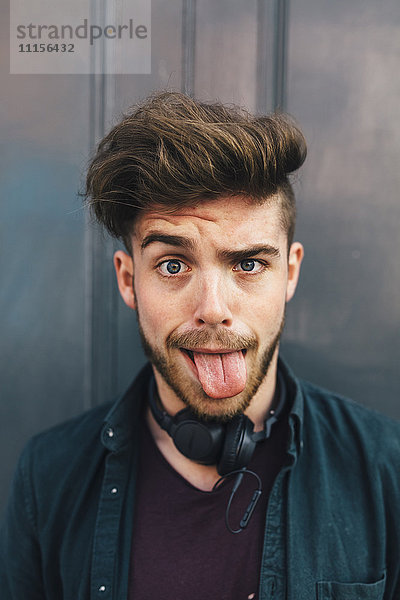 Porträt eines jungen Mannes  der die Zunge herausstreckt