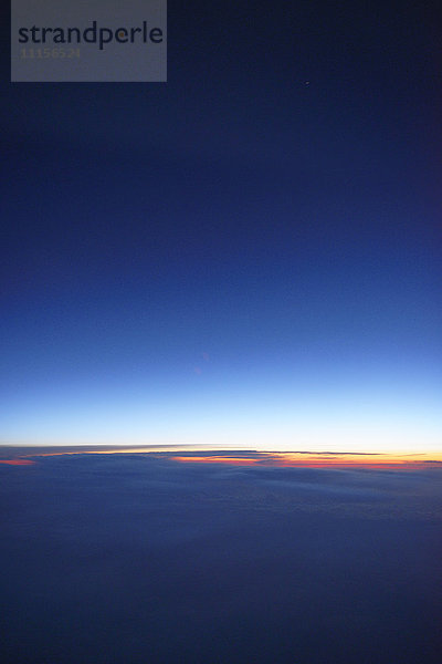 USA  Blick aus dem Flugzeugfenster bei Sonnenuntergang über den Wolken