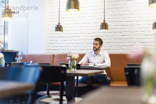 Geschäftsmann sitzend in einem Café mit Tasse Kaffee