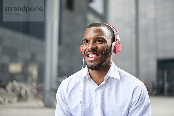 Porträt eines glücklichen Geschäftsmannes beim Musikhören mit Kopfhörern