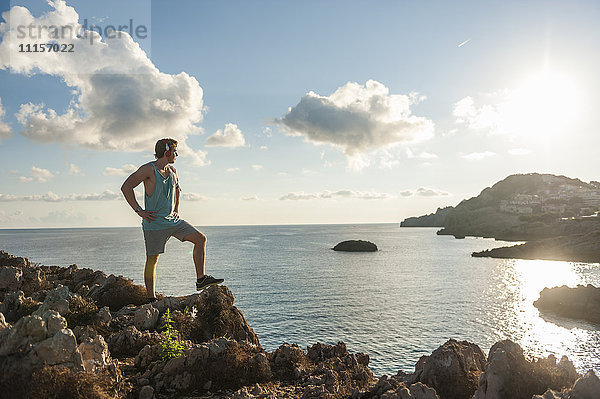 Spanien  Mallorca  Sportler am Morgen an der Felsenküste stehend