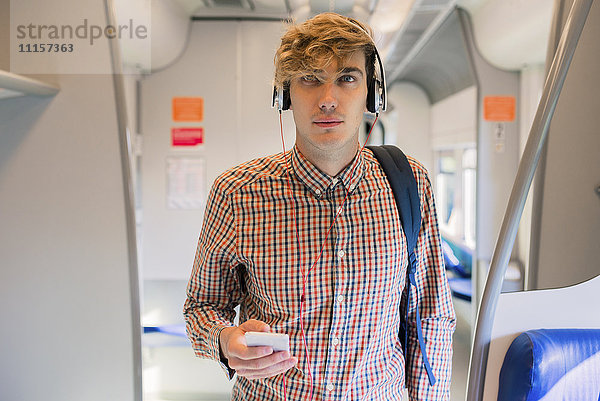 Junger Mann beim Musikhören mit Kopfhörern im Zug