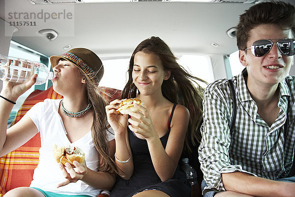 Drei Teenager-Freunde bei einem Snack im Auto