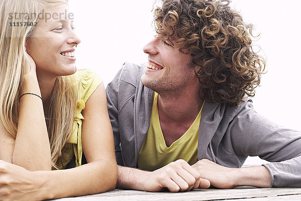 Lächelndes junges Paar auf einem Steg liegend