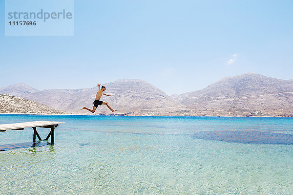 Griechenland  Kykladen  Amorgos  Ägäis  nackter Mann  der von einem Holzsteg springt.