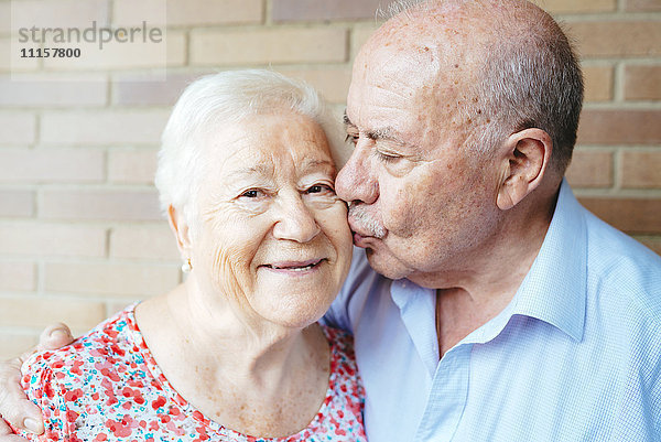 Ein älterer Mann  der seine Frau küsst.