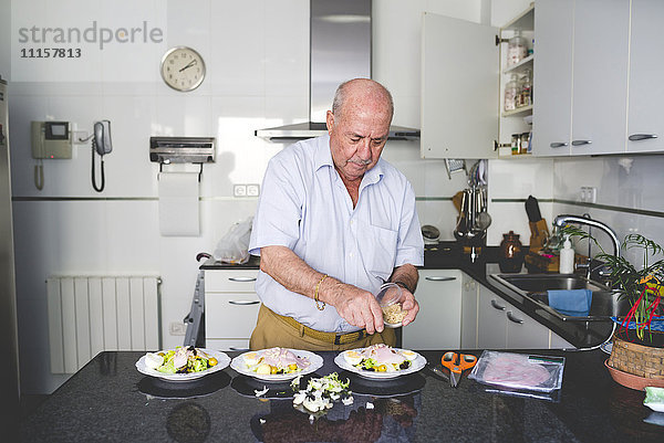 Senior Mann bereitet Salat in der Küche zu.