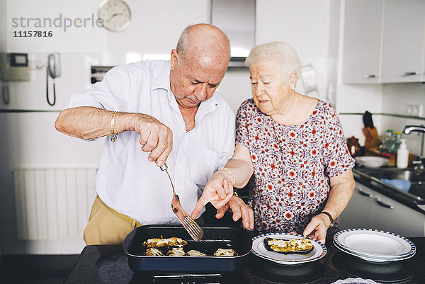 Seniorenpaar serviert gefüllte Auberginen in der Küche