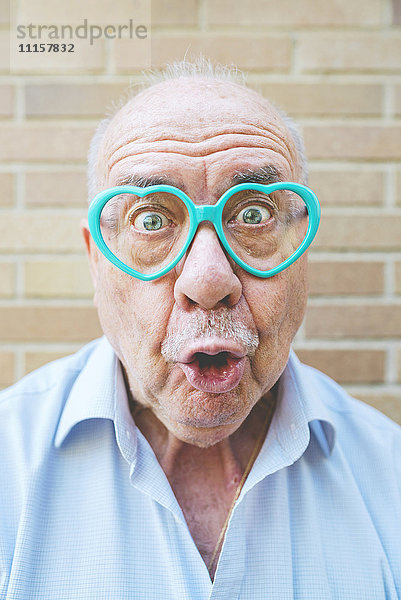 Porträt eines älteren Mannes mit herzförmiger Brille und lustigen Gesichtern
