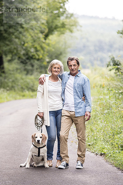 Porträt eines glücklichen Seniorenpaares mit Hund in der Natur