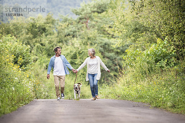 Seniorenpaar auf einem Spaziergang mit Hund in der Natur