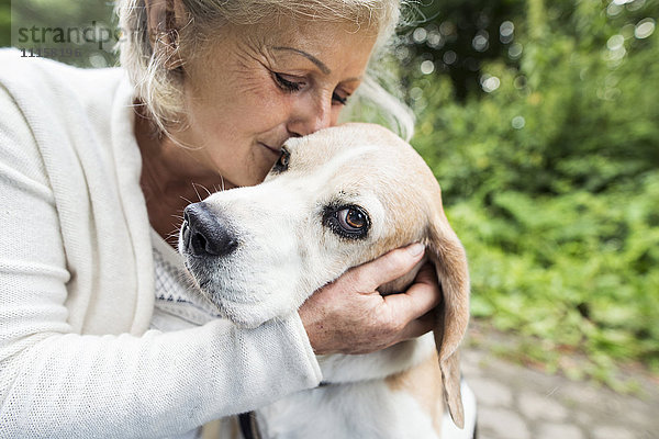 Glückliche Seniorin beim Kuscheln ihres Hundes