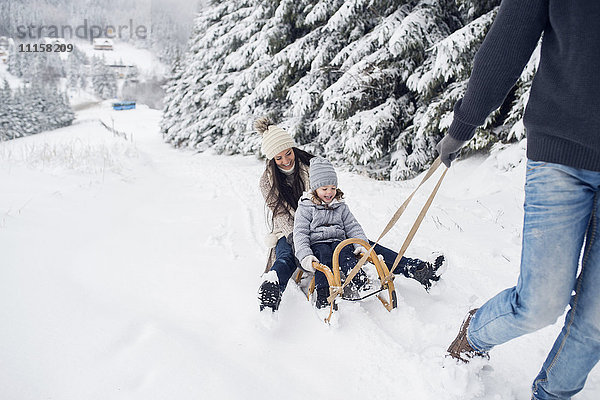 Glückliche Familie mit Schlitten in der Winterlandschaft