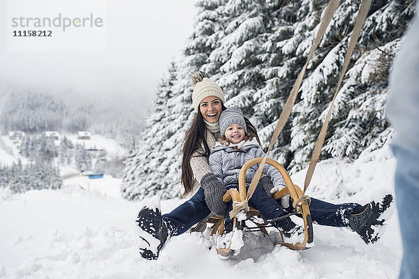 Glückliche Familie mit Schlitten in der Winterlandschaft