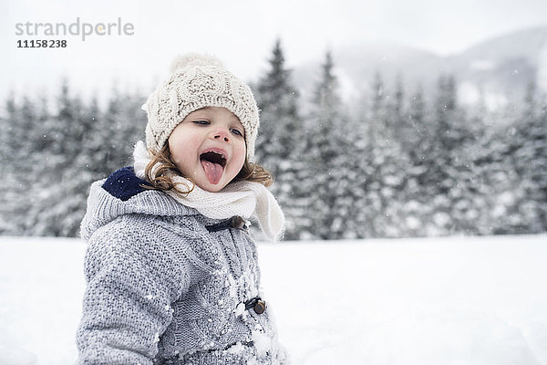 Mädchen in Winterlandschaft mit der Zunge Schneeflocken fangen