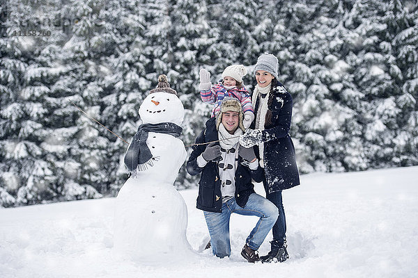 Familie posiert am Schneemann