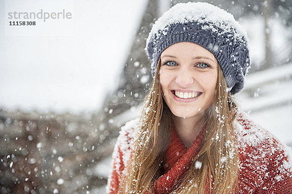 Porträt einer lächelnden jungen Frau bei starkem Schneefall