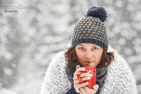 Porträt einer Frau mit Pudelmütze und Heißgetränk im Winter