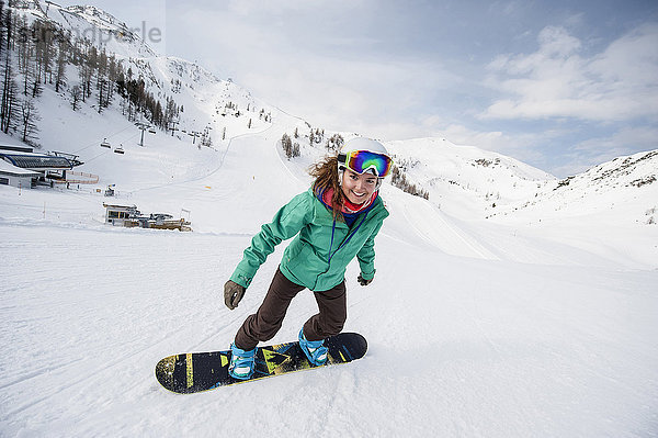 Österreich  Altenmarkt-Zauchensee  lächelnde junge Frau beim Snowboarden