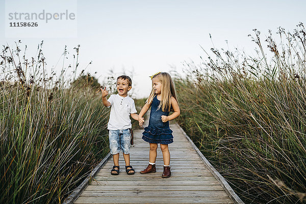 Zwei kleine Kinder spielen zusammen auf einer Strandpromenade in der Natur.