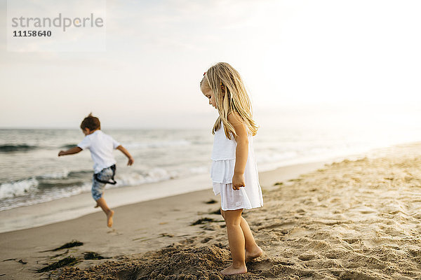 Kleiner Junge und Mädchen spielen am Strand