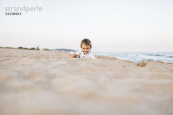 Lächelnder kleiner Junge spielt am Strand