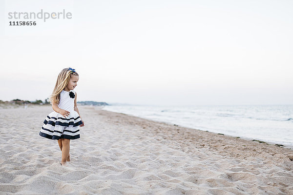 Fashionalble kleines Mädchen spielt am Strand