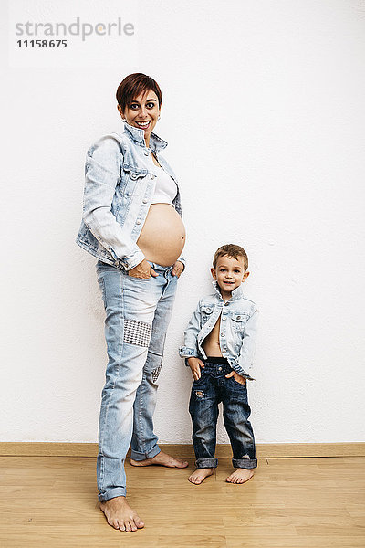 Schwangere Mutter und kleiner Sohn stehend mit Händen in den Taschen