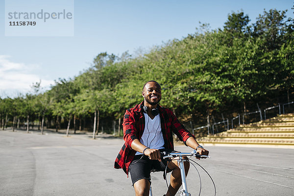 Lächelnder Mann auf dem Fahrrad durch einen Park