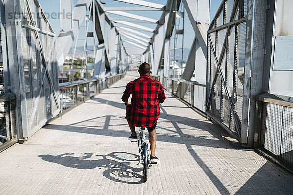 Mann fährt Fahrrad auf einer Brücke