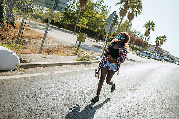 Junge Frau mit Skateboard auf der Straße