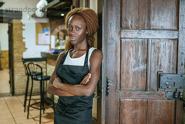 Porträt einer jungen Kellnerin an der Tür einer Bar