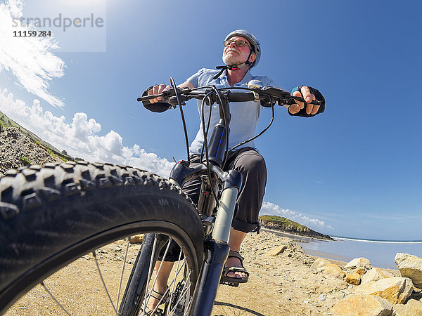 Frankreich  Bretagne  Senior auf elektrischem Mountainbike auf dem Küstenweg