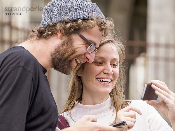 Lächelndes junges Paar beim Blick auf das Smartphone